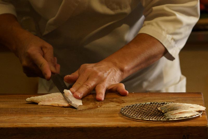 Sushimästaren som skär upp en sushibit